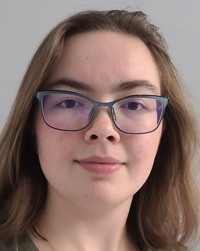 A young woman with dark blonde hair wears glasses