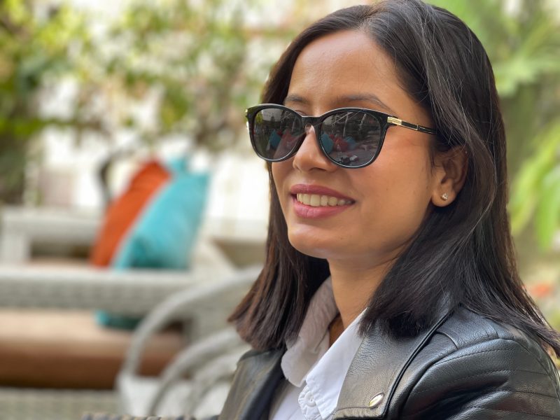 Young woman with dark hair wearing sunglasses.
