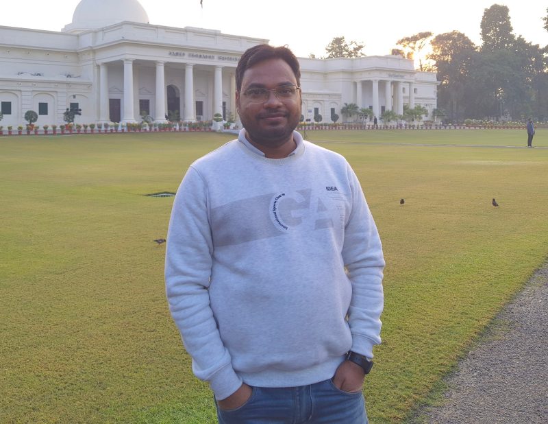 Man in sweatshirt stand in front of university building