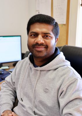Man in sweatshirt seated at desk.