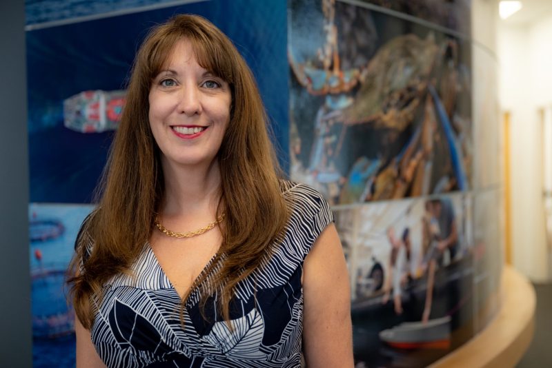 Wendy Stout in front of marine mural in the Virginia Tech Coastal Collaborator office