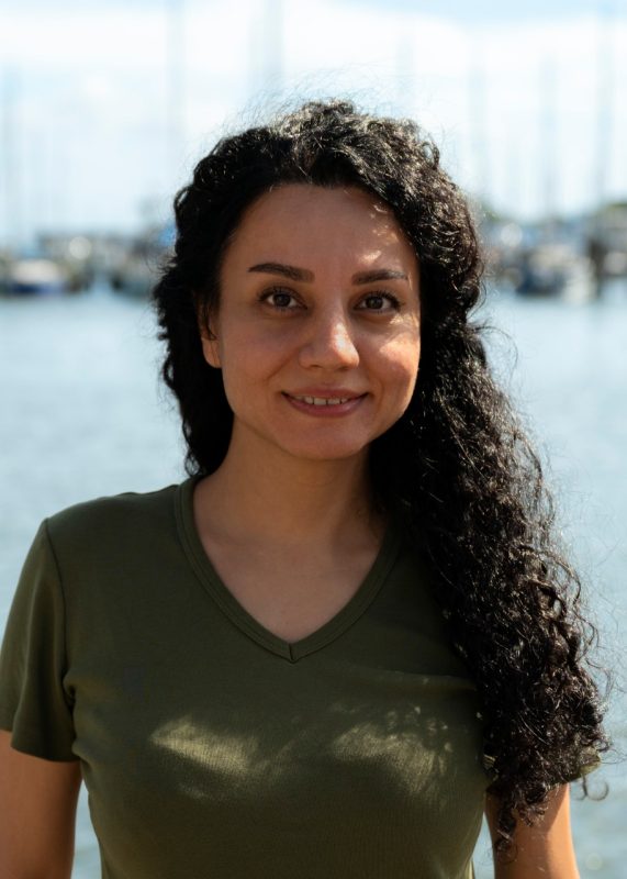 Shabnam Jeibouei standing in front of the river and boats in Hampton.