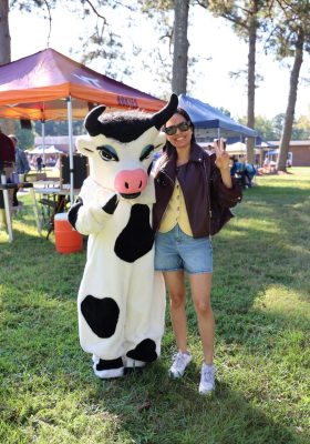 A woman smiles standing beside another person in a black and white cow costume