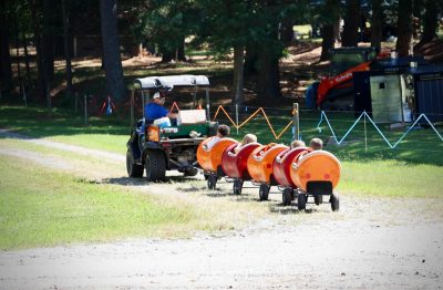 A golf cart pulls a children's barrel train