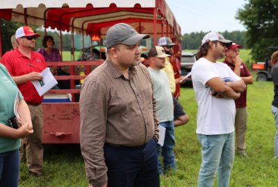 People stand beside a red wagon alongside a field