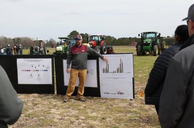 Man in hat and jacket presents data in the field during the Cover Crop tour at Tidewater AREC.