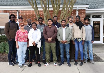 University group of students and faculty stand outside of AREC building.
