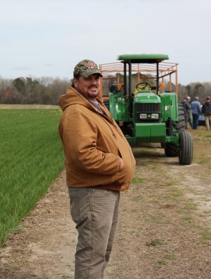 Man in field wearing hat with tractor in the background