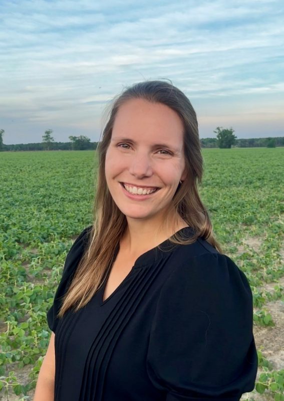 Woman wearing black top standing in field.