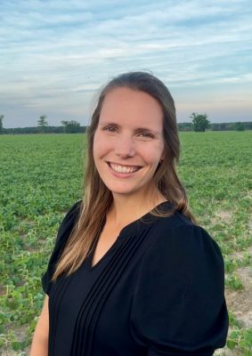 Woman wearing black top standing in field.