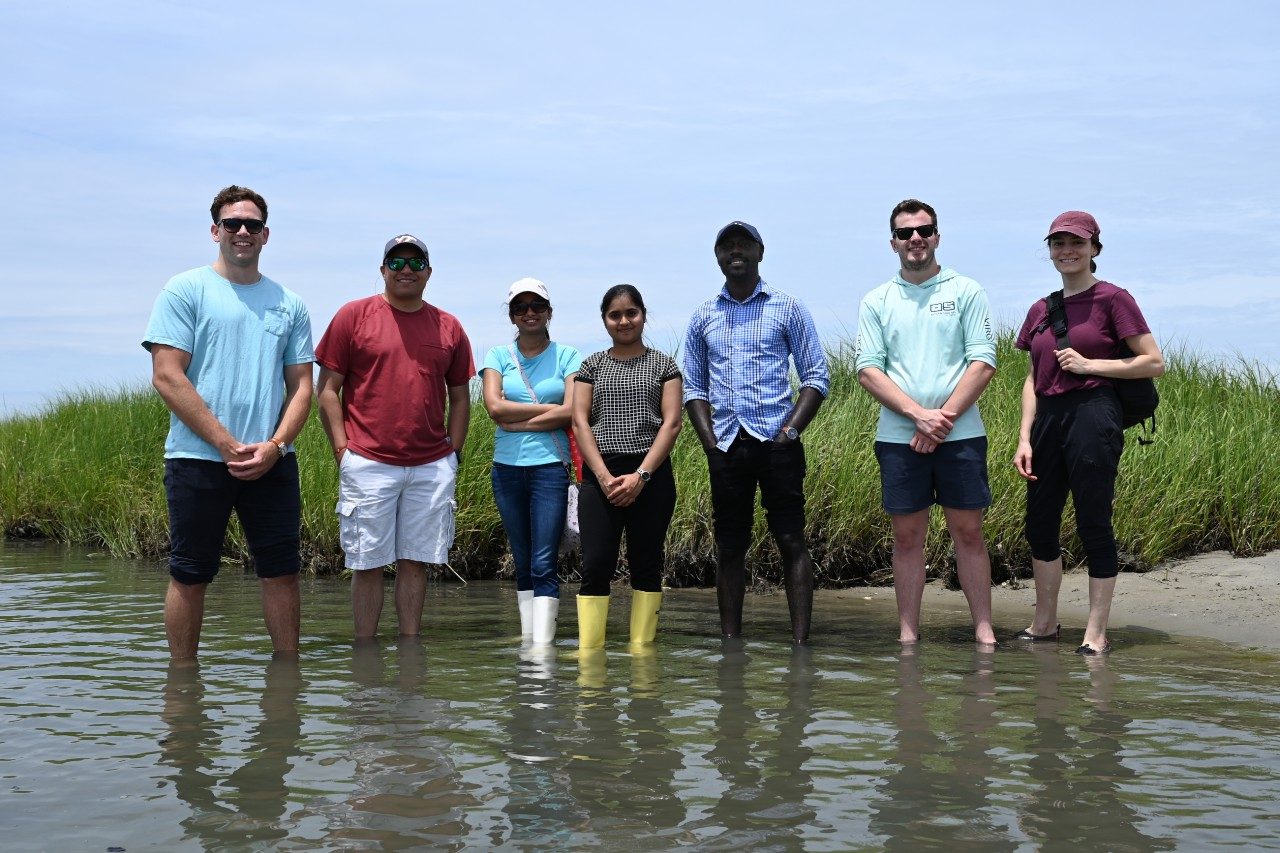 Virginia Seafood AREC team stands in water at an oyster farm