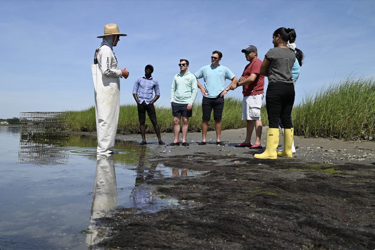 Virginia Seafood AREC team speaks with an oyster farmer on the shore