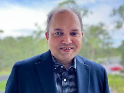 A man in a blue jacket and shirt smiles for the camera.